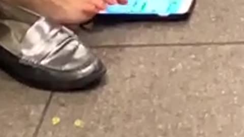 Woman types a text message with her bare toe at subway station