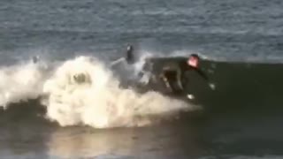 Wet suit surfer rides board towards dock falls off