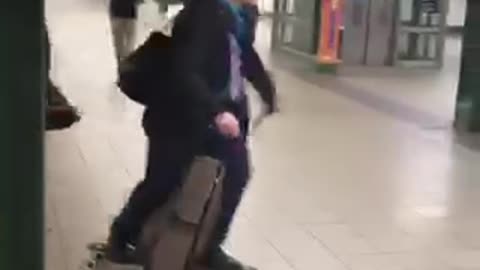 Old man in subway station rides on his skateboard, pushes himself with two canes, dancing to music