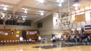 Girl makes basketball shot from behind her back at high school gym