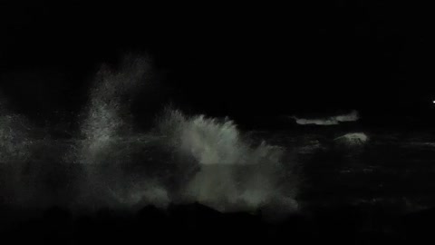 Waves crashing on the breakwater at night