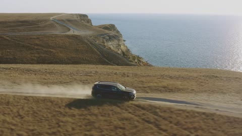 Aerial View of Car Driving Along Coastal Road