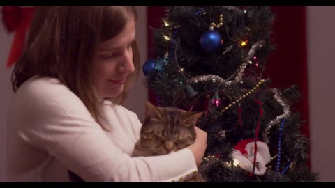 Young woman lifts up and cuddles a cat with blinking lights in background - slow motion