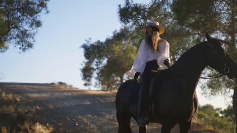 Wide shot portrait of gorgeous slim Caucasian young woman sitting on back of purebred horse