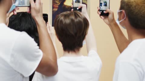 people taking A picture of painting Mona Lisa.