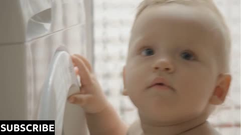 Close-up shot of one year old baby is curious about the washing machine and its buttons