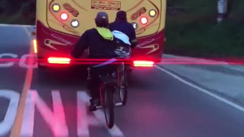 Chicos en bicicleta se enganchan para viajar detrás de un ómnibus