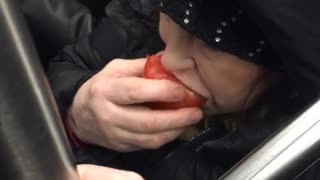 Woman eats a whole tomato on subway train