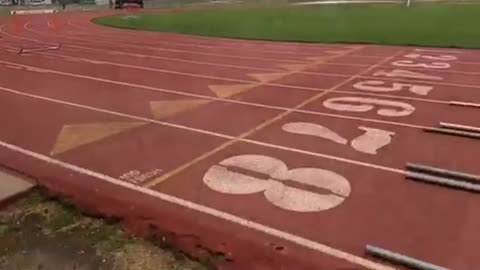 Girl trips on orange track hurdle