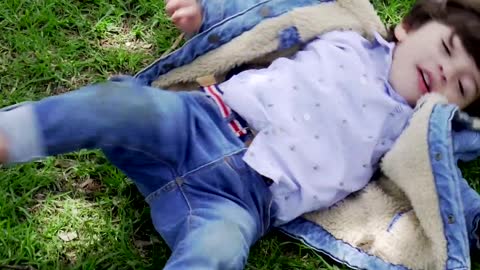 A Kid Playfully Rolling Herself On The Grass