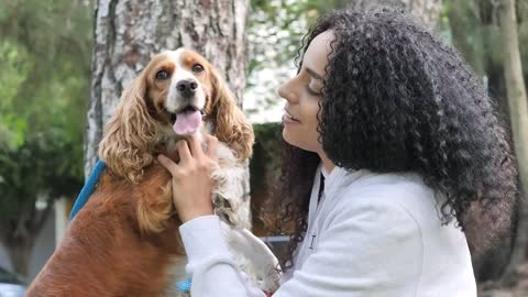 Girl in a park carrying and petting her Cocker Spaniel