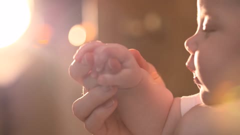 A baby holds his mother's hand