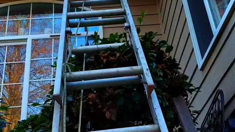 Using an extension ladder stabilizer to climb onto your roof.