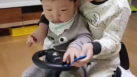 This is a video of babies riding a toy car together.