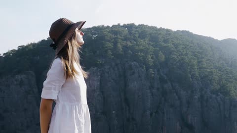 Woman Wearing Hat Standing on a Cliff