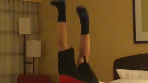 Kid red shirt backflips in hotel room on bed reverse scorpion