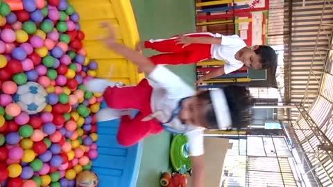 Slowmo red pants girl jumps into ball pit boy falls off