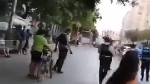 Police attempt to arrest a woman without mask, everyone removes mask to help her.