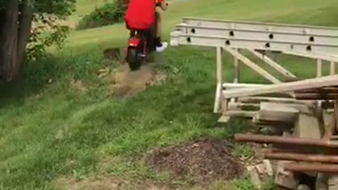 Man in red rides mini bike and falls off