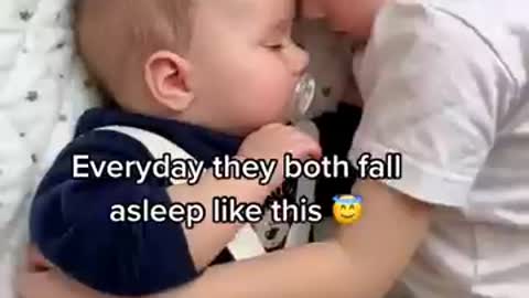 baby brother cuddles baby sister while sleeping