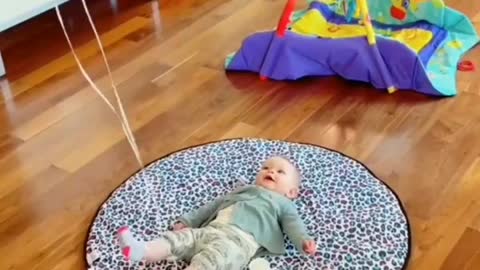 A balloon has been tied in the feet of the little child and he is very happy to see the balloon.