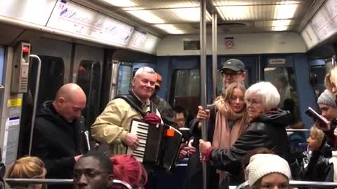 Old man playing accordion on crowded train