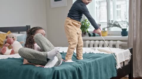 Kids Playing Catch The Bait With Their Cat In The Bedroom