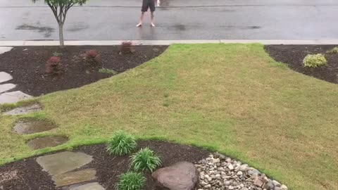 Shirtless guy showers in rain in middle of street