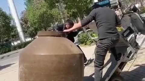 Two guys trying to move a giant vase...wait for it.