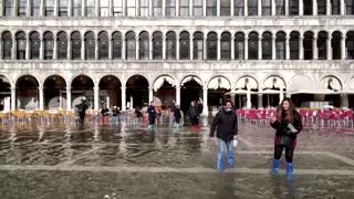 Tourists don colourful shoe covers to wade through Venice