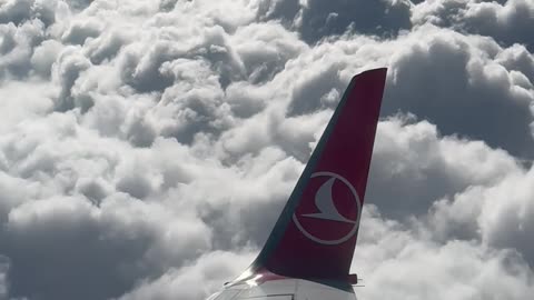 Window View from a Plane Flying above the Clouds