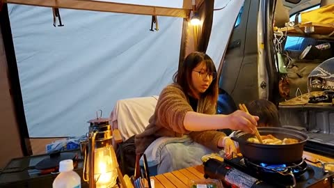 A family with three people camping in the rain