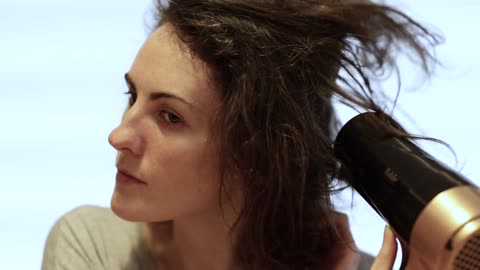 Woman using hairdryer to dry her hair