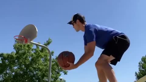 Guy Balances Himself Over Slackline While Throwing Two Basketballs After Dribbling Them