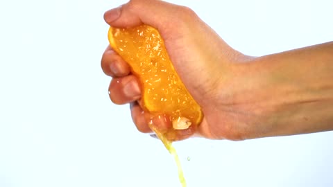 Hand of a person squeezing an orange on a light background