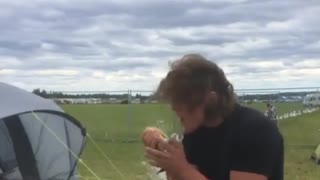 Guy in black at festival cracks beer over head and chugs it