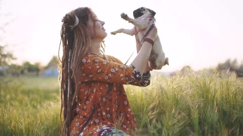 beautiful hippie woman with dreadlocks in green grass with her puppy