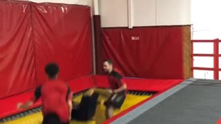 Woman bounces off of trampoline with two friends and face plants into the floor