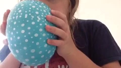 Blonde girl blue balloon sucks in helium falls backwards