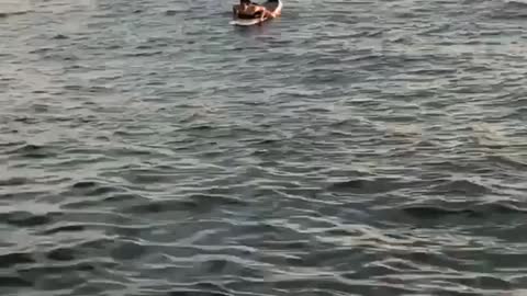 Guy swimming on surfboard in water