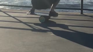 Man balancing on cylinder on pier looking at ocean