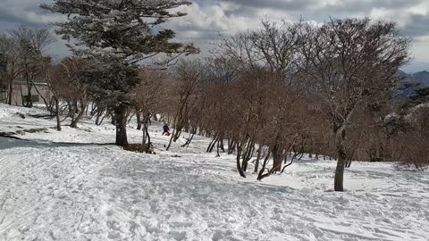 Boy slides down snowy slope very fast and loses his sled down the hill