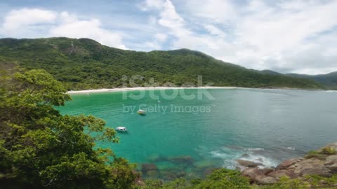 Paradise beach with clear water, blue sky, and mountains Little boats anchored