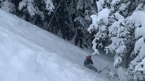 Skier trips off ledge and falls into pile of snow