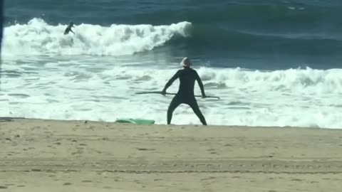 Guy with paddleboard does stretches at the beach with his paddle