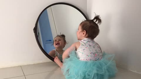 Baby plays with her reflection in the mirror