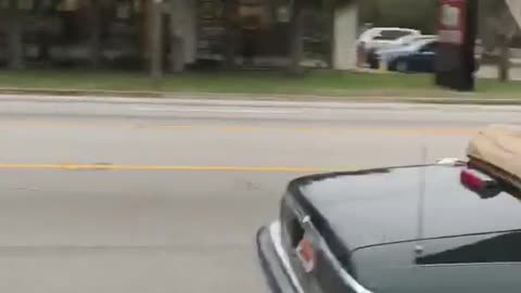 Black topless car drives down highway with unsecured wood board