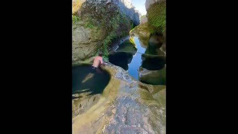 Guy takes a dip and swims underneath rocks through natural pools