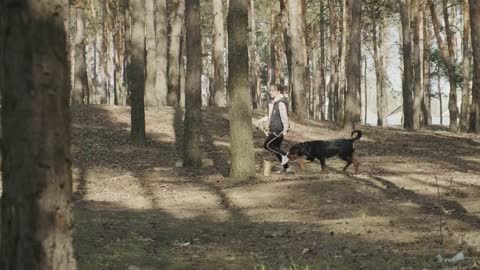 Girl running with her dog among the trees
