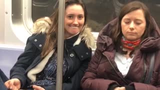 Girl on subway makes silly face at a sleeping woman